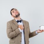 What Are The Hardest Months To Sell A House Successfully? young man in suit sad to sell a house while looking up