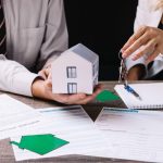 When To Sell A House: Before Or After Buying A New One? realtor holding a miniature knowing when to sell a house to the client holding keys