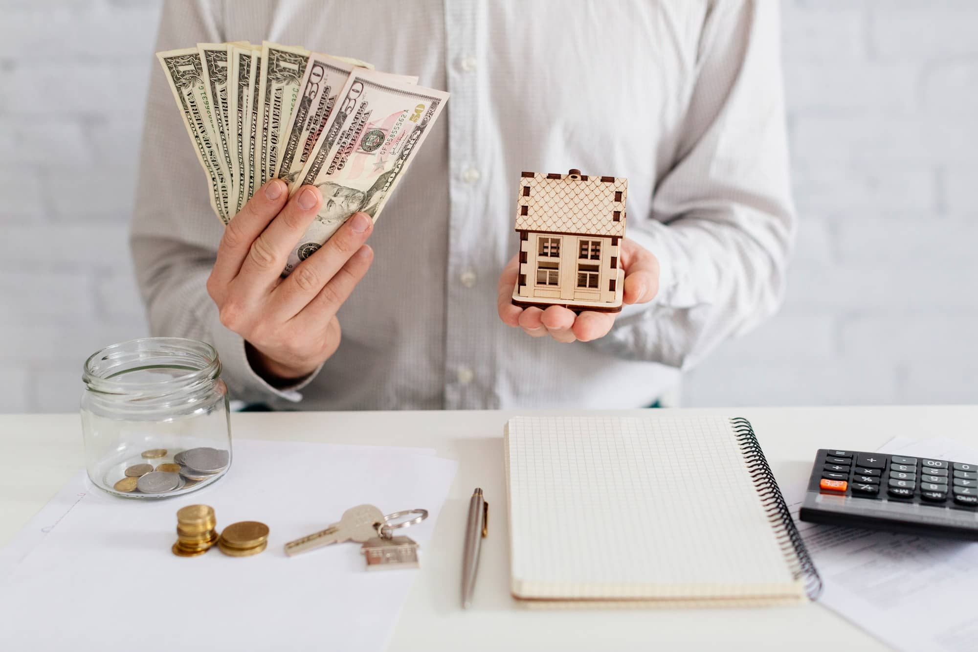 A man holding a miniature house and money