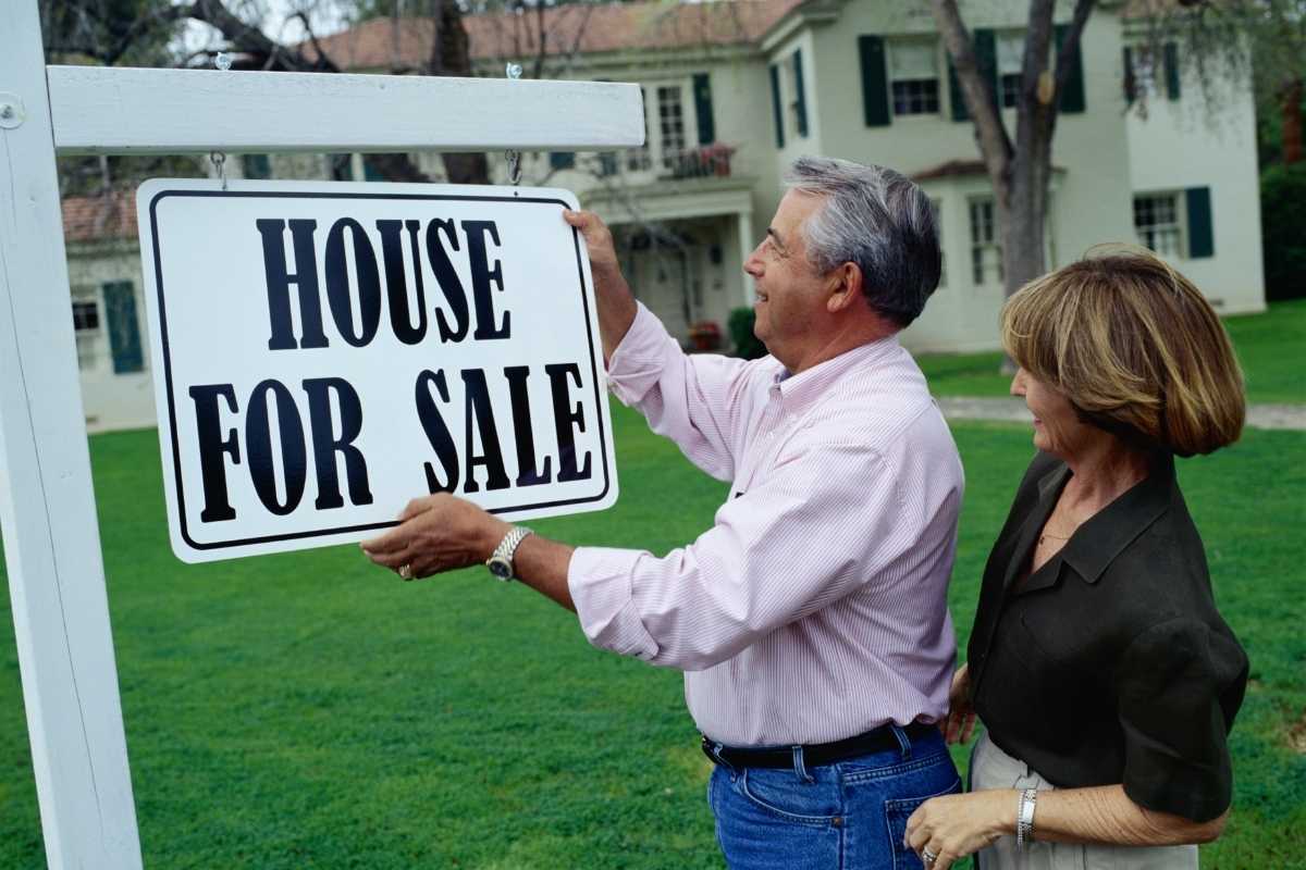 Couple holding sign for selling house