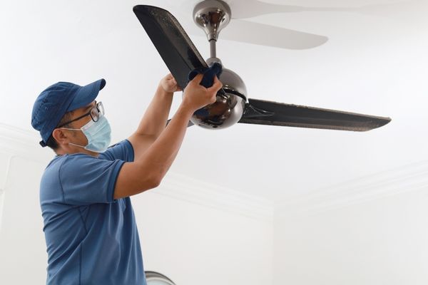 A man cleaning a ceiling fan