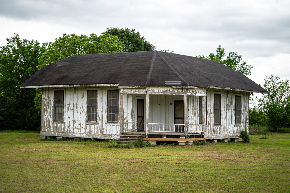 Weathered white house needing repairs demonstrates selling a house in poor condition options.