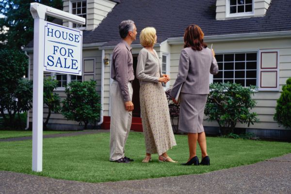 sell my house for cash Clients talking to a real estate agent about a house.