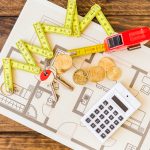 Blueprint with measuring tape and calculator showing ROI home improvements planning tools.