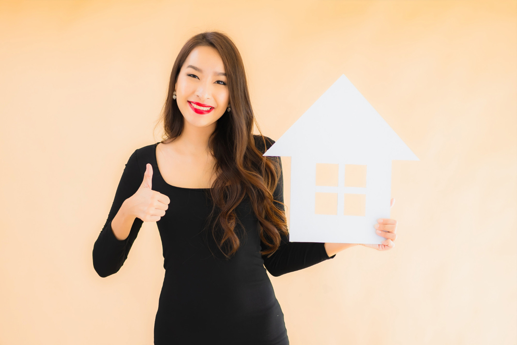 Happy homeowner holding house cutout representing tips for increasing your home's value today.
