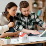 Boston Median Home Price Insights And Trends Young homebuyers analyzing Boston home price insights with miniature house on table together.
